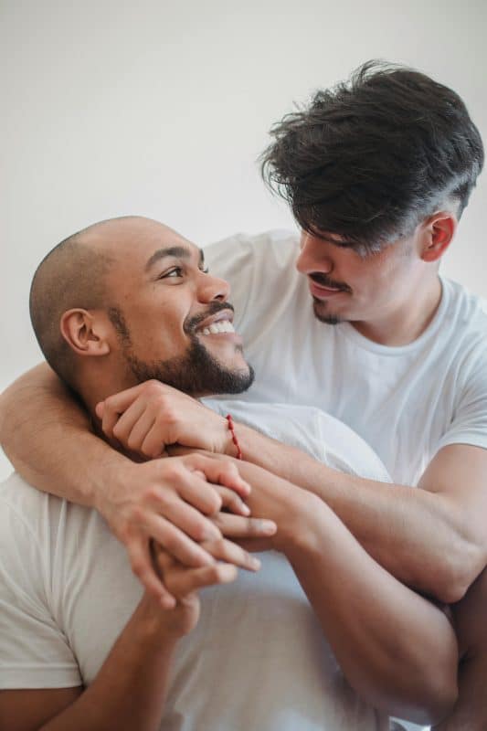 Couple d'homme se tenant dans les bras en se souriant. Cette photo illustra la déconstruction des préjugés pour obtenir une sexualité positive.