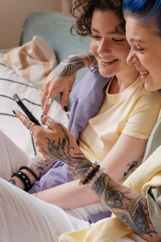 Couple de femmes regardant un téléphone avec complicité. La communication comme pilier de leur complicité et de leur sexualité positive